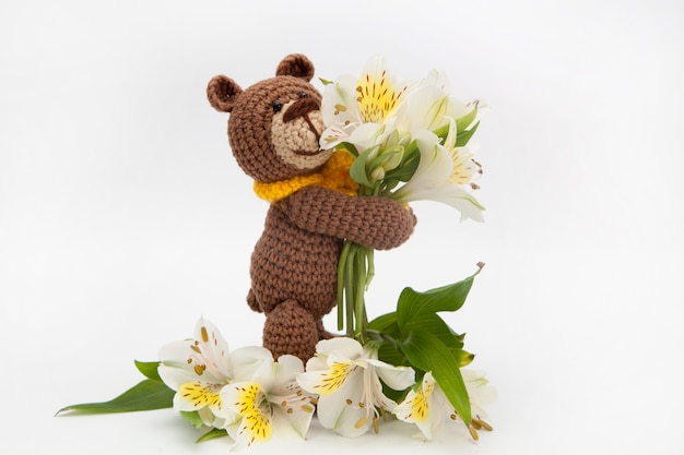 Urso marrom pequeno com flores brancas, brinquedo feito malha, feito a mão. Amigurumi