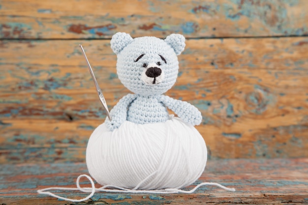 Urso pequeno de malha em um velho de madeira. Brinquedo artesanal de malha. Amigurumi