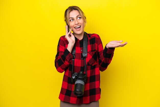 Uruguayische Fotografin isoliert auf gelbem Hintergrund, die mit jemandem ein Gespräch mit dem Handy führt