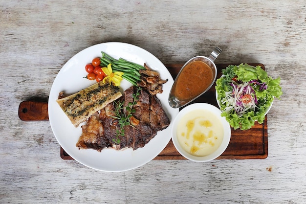 US Black Angus Rib Eye Steak mit Chilisauce und Salat, serviert in einem Gericht isoliert auf grauem Hintergrund Seitenansicht