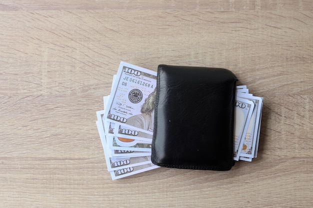 US-Dollar-Geld in schwarzer Ledergeldbörse auf Holztisch. Ansicht von oben.