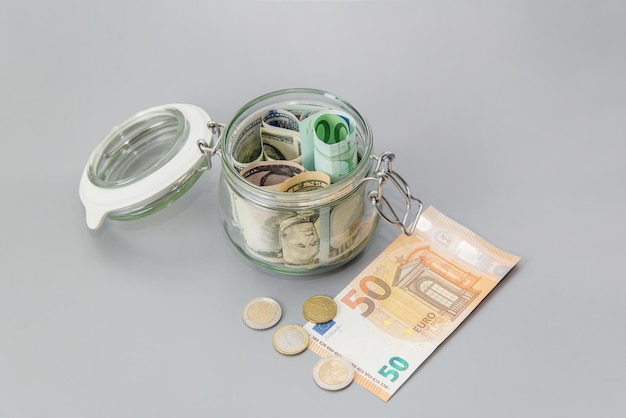 US-Dollar und Euro-Banknoten in einem Glas Scheine und Münzen in einem Sparschwein Sparen Sie Geld