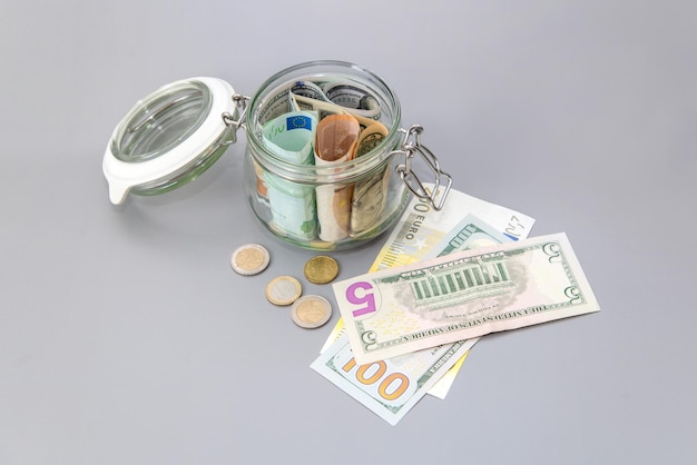 US-Dollar und Euro-Banknoten in einem Glas Scheine und Münzen in einem Sparschwein Sparen Sie Geld
