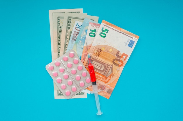 US-Dollar und Euro-Banknoten. medizinische Maske, Impfstoffspritze und rosa Pillen, Pillenblase. Wirtschaftskrise. Gesundheitsausgaben. Ausbruch des Coronavirus.