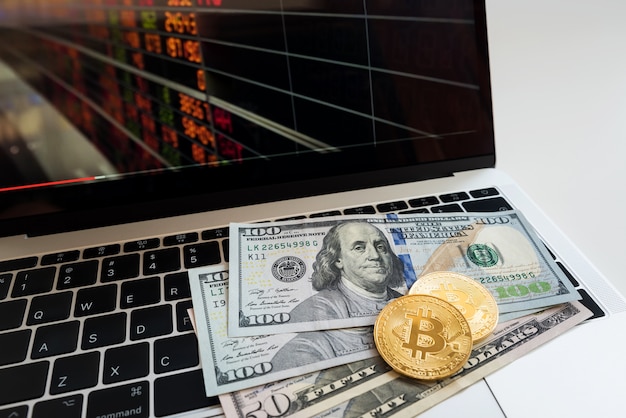 USA-Banknote mit Bitcoin und Daten über Laptop für Geschäftshintergrund