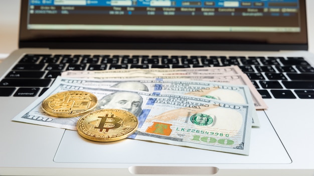 USA-Banknote mit Bitcoin und Daten über Laptop für Geschäftshintergrund