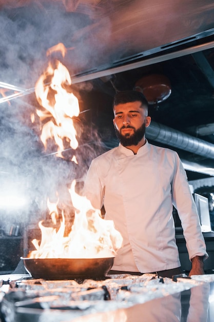 Usa frigideira chef em uniforme branco cozinhando comida na cozinha dia ocupado no trabalho