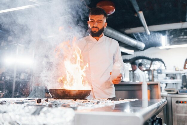 Usa frigideira Chef em uniforme branco cozinhando comida na cozinha Dia ocupado no trabalho