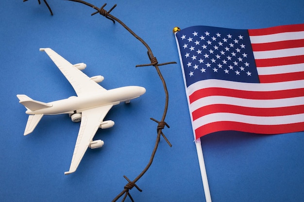 USA geschlossenes Luftraumkonzept Spielzeugflugzeug Stacheldraht und Flagge auf blauem Hintergrund