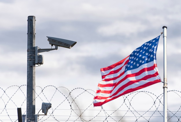 USA-Grenze, Überwachungskamera, Stacheldraht und USA-Flagge, Konzeptbild