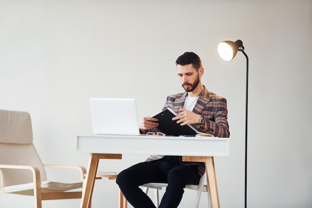 Usa laptop Jovem empresário estiloso de terno dentro de casa Concepção de sucesso