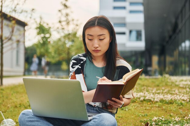 Usa laptop La mujer asiática joven está al aire libre durante el día