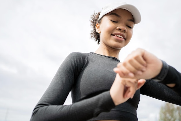 Usa un reloj de fitness y un brazalete de seguimiento de calorías, un corredor, una atleta femenina, hace un entrenamiento activo corriendo