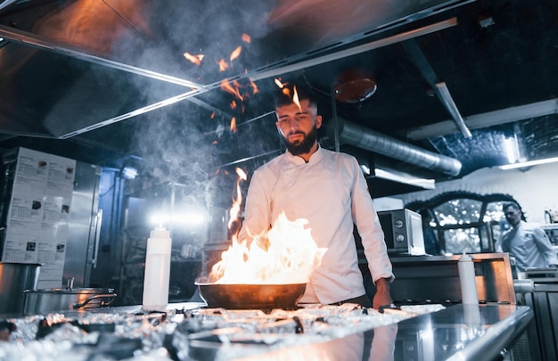 Foto usa sartén chef en uniforme blanco cocinando comida en la cocina día ajetreado en el trabajo