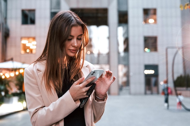 Usa telefone Linda jovem europeia está ao ar livre na cidade durante o dia