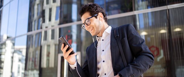 Usa el teléfono lee el administrador de mensajes un hombre en un traje de negocios va a la oficina