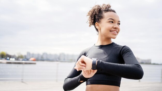 Usa um relógio de fitness e uma pulseira de rastreador para calorias um corredor uma atleta feminina faz um treino ativo correndo