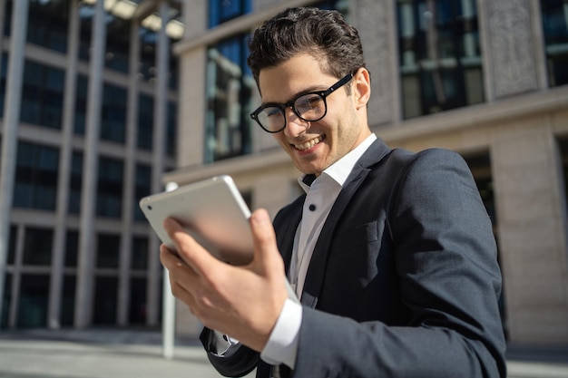 Foto usa um tablet escreve uma mensagem para um cliente um homem de óculos e um terno formal um empresário