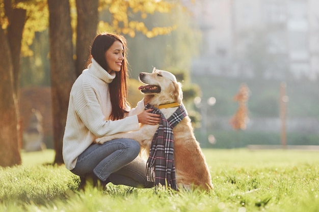 Usando la bufanda Mujer joven pasea con Golden Retriever en el parque