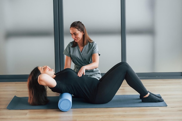 Usando colchoneta de yoga La mujer está en el centro de salud recibiendo ayuda del médico