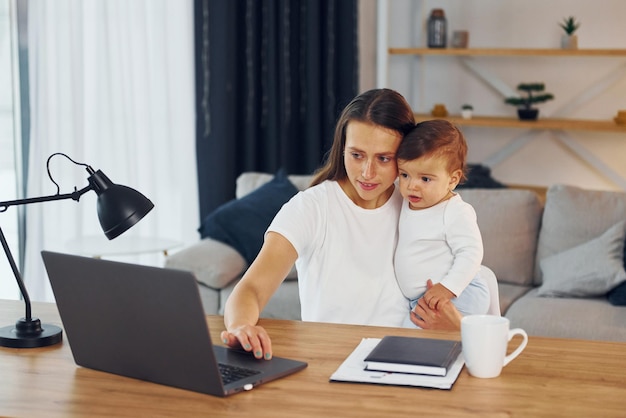 Usando la computadora portátil Madre con su pequeña hija está en casa juntos