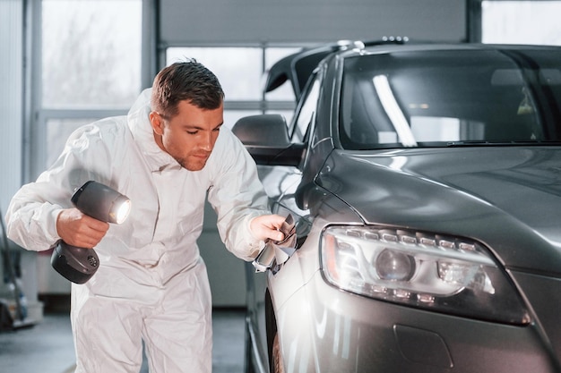 Usando equipamento especial O homem de uniforme está trabalhando no auto serviço