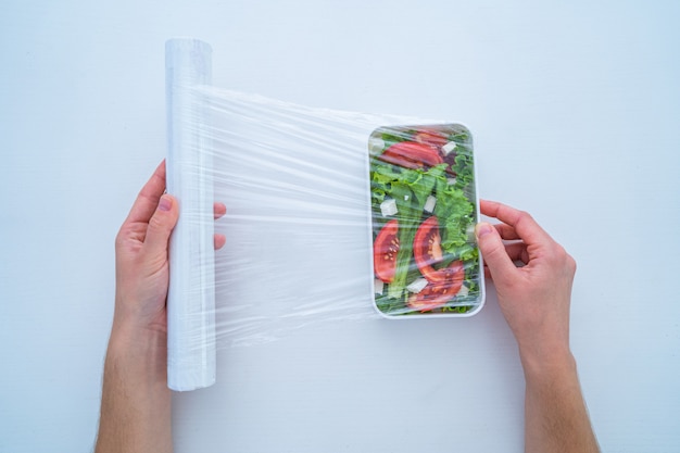 Usando filme plástico de polietileno para armazenamento de alimentos na geladeira em casa