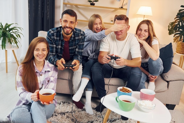 Foto usando joysticks para jogar videogame grupo de amigos fazem festa dentro de casa juntos