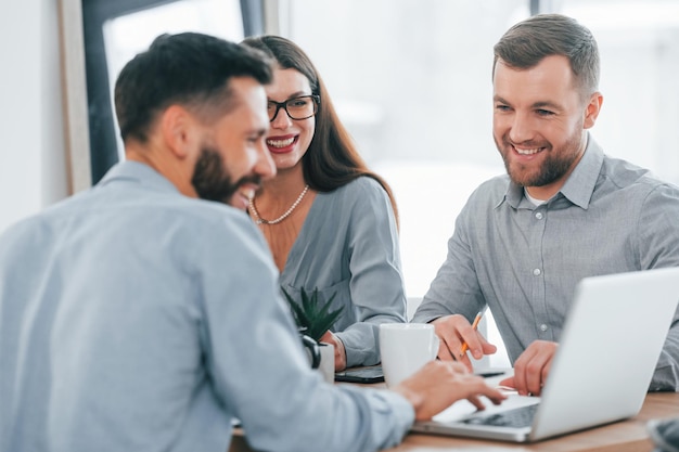 Usando laptop Grupo de empresários que trabalham no projeto no escritório