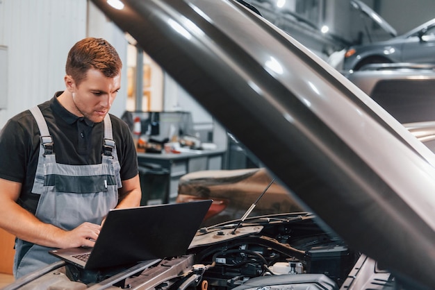 Usando laptop Homem de uniforme está trabalhando no serviço automático