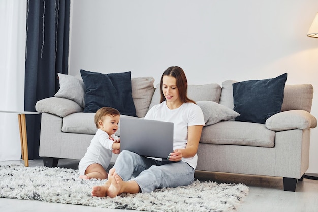 Usando laptop Mãe com sua filha está dentro de casa juntos