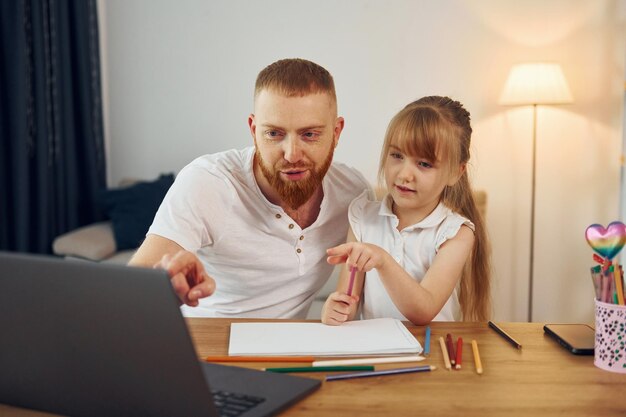 Usando laptop Pai com sua filha está em casa juntos