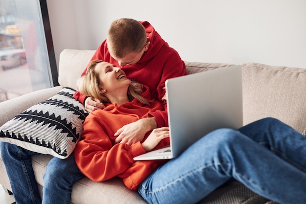 Usando laptop que está nas pernas Jovem casal adorável juntos em casa passando fim de semana e feriados juntos