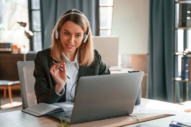 Foto usando laptop uma jovem e bonita mulher de roupas formais está trabalhando no escritório