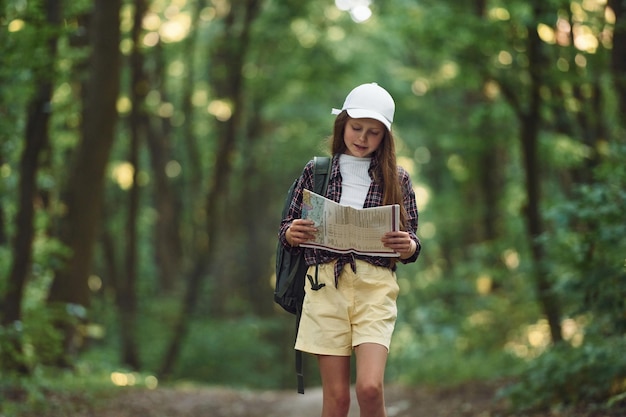 Foto usando el mapa la niña está en el bosque durante el día de verano descubriendo nuevos lugares