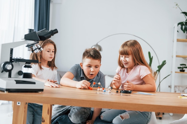 Usando microscópio crianças se divertindo na sala doméstica durante o dia juntos