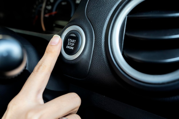 Usando o botão para ligar e desligar o motor o dedo da mulher está pressionando conforto ao dirigir um carro é algo que todos desejam