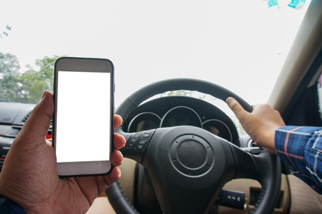 Usando o dispositivo de telefone móvel ao dirigir vista de tiro recortada homem olhando para o telefone inteligente em um carro