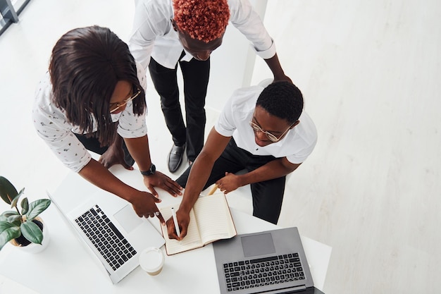 Usando o mesmo laptop para o projeto Grupo de empresários afro-americanos trabalhando juntos no escritório