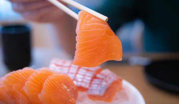 Usando pauzinhos sashimi de salmão Sashimi é um prato popular de restaurantes japoneses