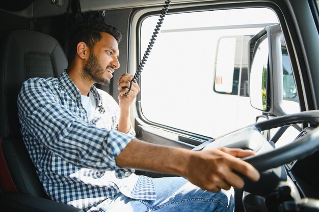 Foto usando la radio el joven camionero está con su vehículo durante el día.