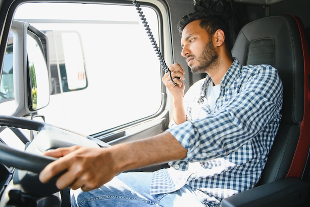 Foto usando la radio el joven camionero está con su vehículo durante el día