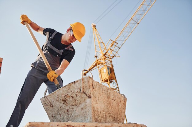 Usando showel Trabalhador da construção em uniforme e equipamento de segurança tem trabalho na construção