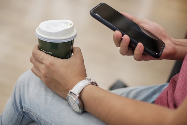 Usando smartphone entre beber café quente.