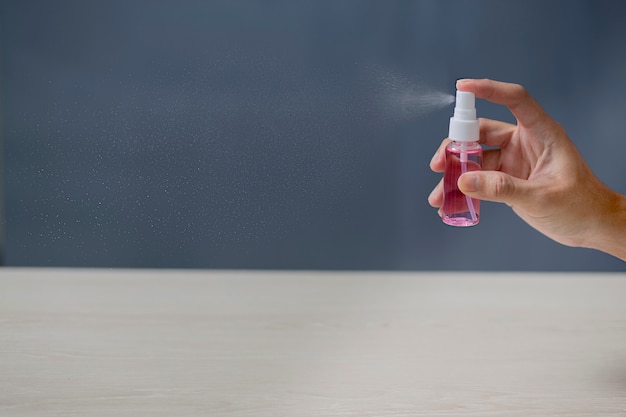 Usando spray de álcool para limpar as mãos em casa