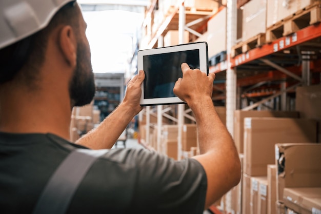 Usando la tableta digital Foreman está en el negocio de distribución de envío de almacén