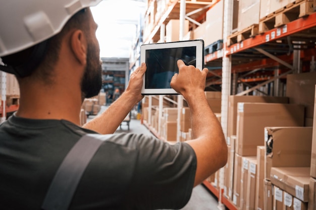 Usando la tableta digital Foreman está en el negocio de distribución de envío de almacén