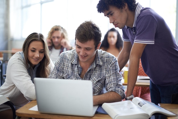 Usando todos os recursos para seu projeto Foto de um grupo de estudantes universitários trabalhando em laptops em sala de aula