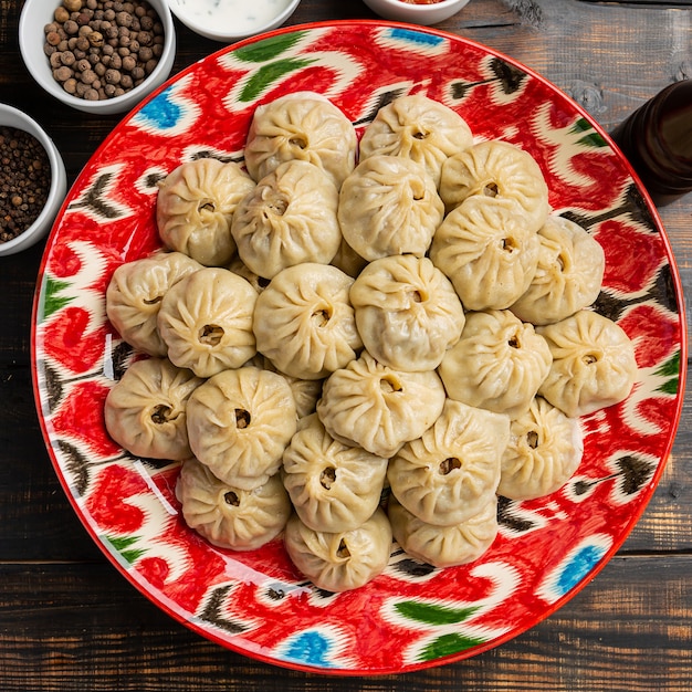 Foto usbekisch zubereitete gekochte manti oder manty knödel in einer traditionellen schüssel auf rustikalem holztisch.