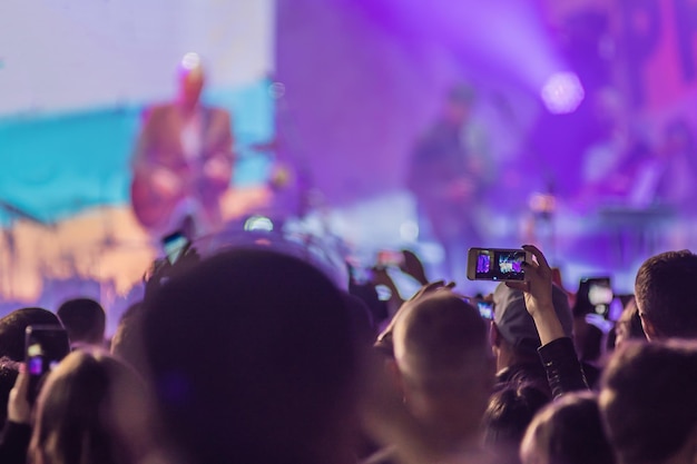 Use la grabación móvil avanzada de conciertos divertidos y una hermosa iluminación Imagen sincera de la multitud en un concierto de rock Primer plano de la grabación de video con un teléfono inteligente Disfrute del uso de la fotografía móvil